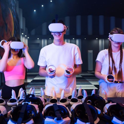 A team of young friends using virtual reality VR equipment on an arena. Neon lights